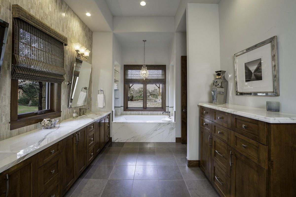 Luxury bathroom with long vanity, marble countertop, and a view of the outdoors.