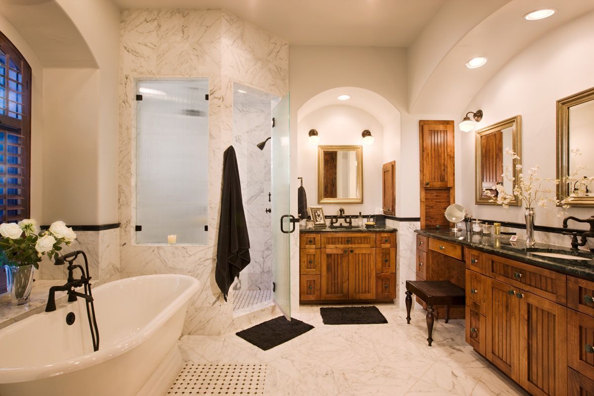 Spacious bathroom with white tile, clawfoot tub, and wooden cabinets. Shower with frosted glass.