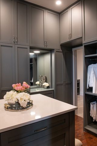 Gray walk-in closet with center island, mirror, and floral arrangement.