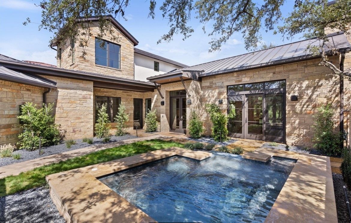 Stone house with a small pool in a courtyard.