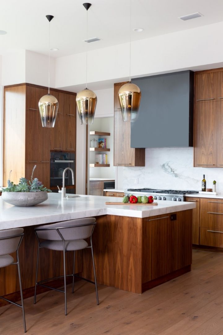 Modern kitchen with wood cabinets, white countertops, island, and pendant lights.