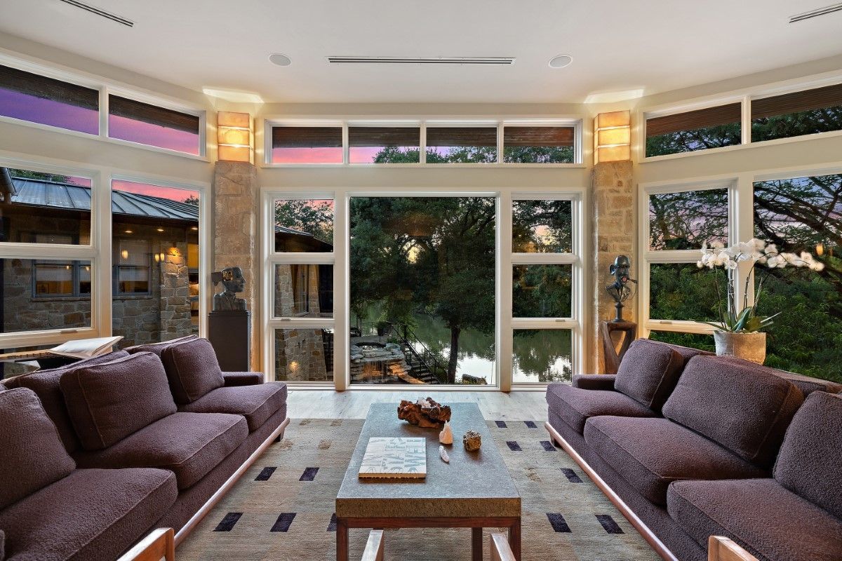 Living room with two purple couches, large windows, and a view of trees and sky.