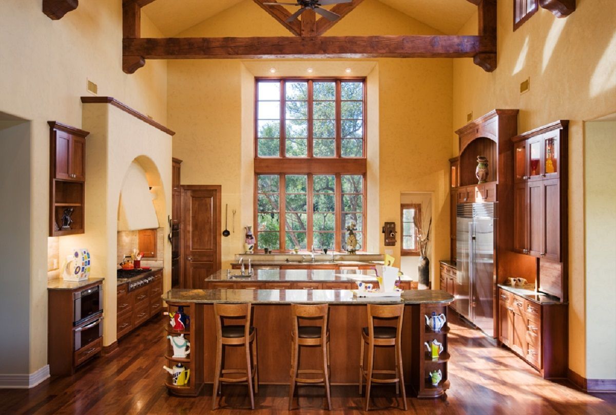 Spacious kitchen with high ceilings, wood cabinets, and large windows overlooking trees
