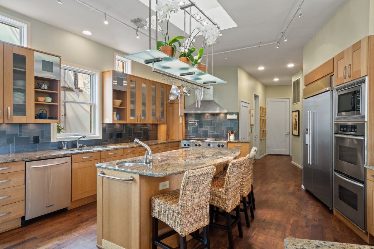 Spacious kitchen with wood cabinets, island with seating, stainless steel appliances, and natural light.