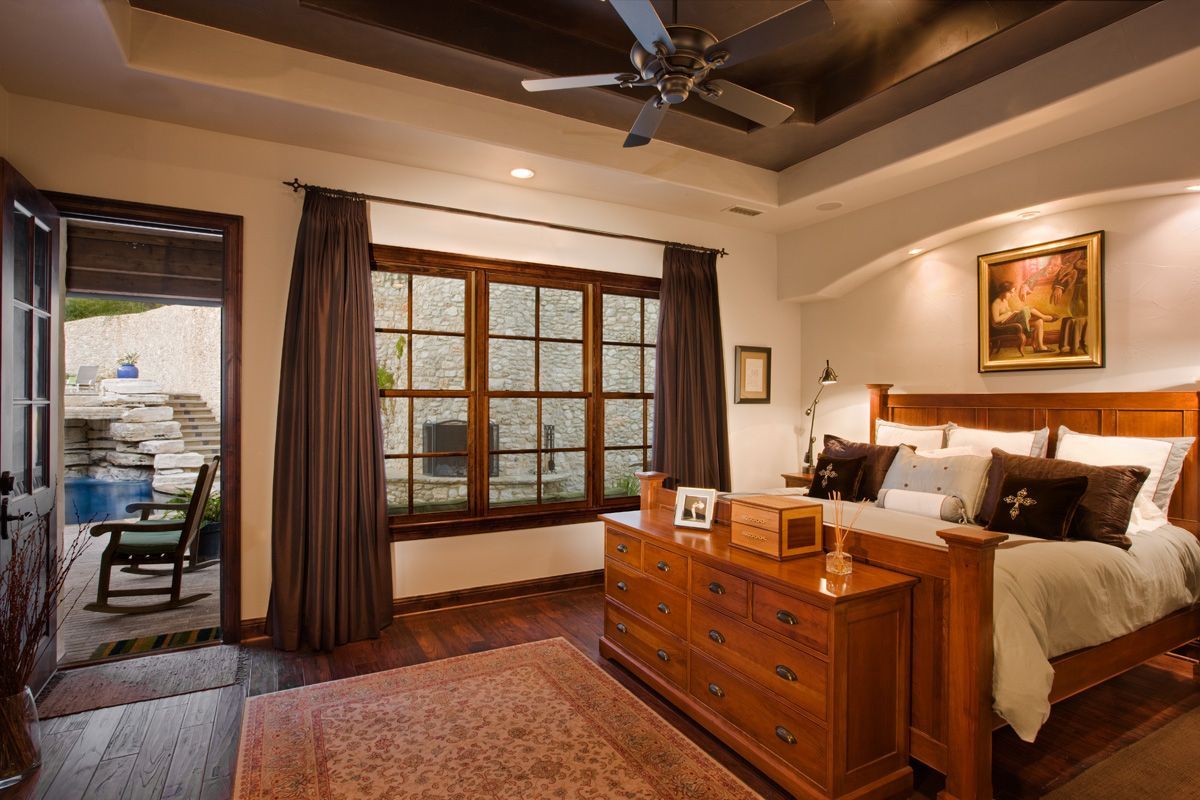 Bedroom with a wooden bed, dresser, window, and open door to a patio.