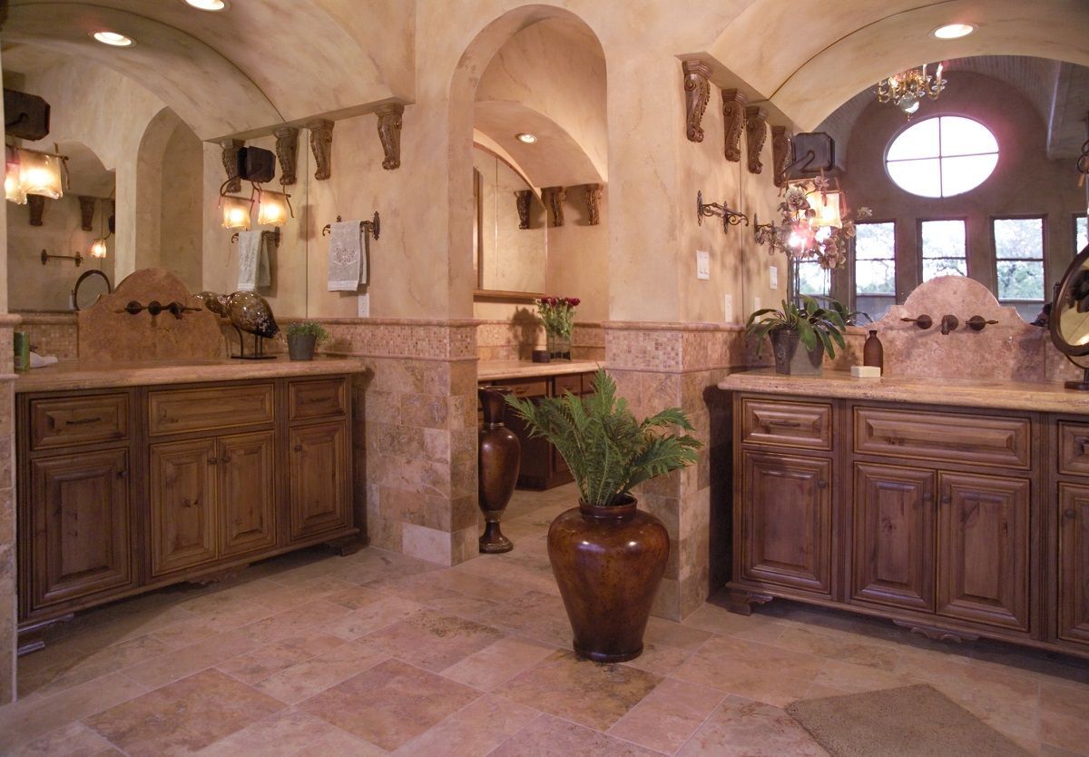 Luxurious bathroom with stone tile, wooden vanities, and arched doorways.