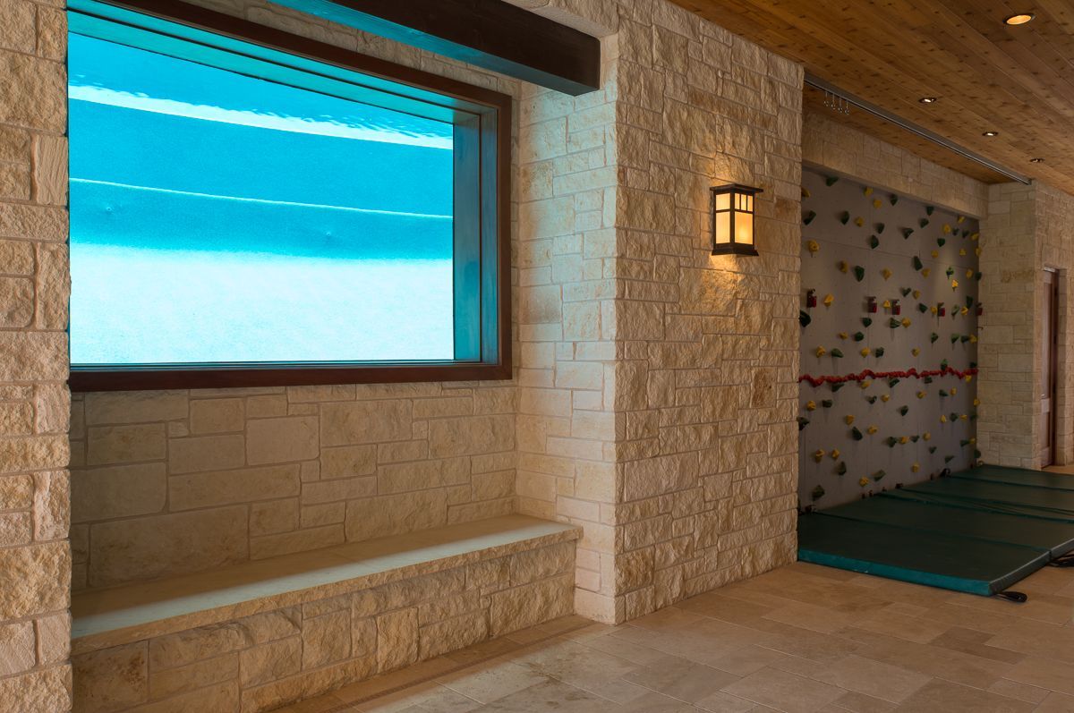 Interior with stone walls, window with blue light, climbing wall, and bench.
