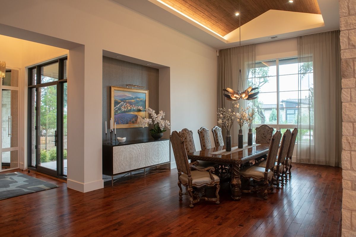 Elegant dining room with dark wood table, ornate chairs, and a large window with sheer curtains.