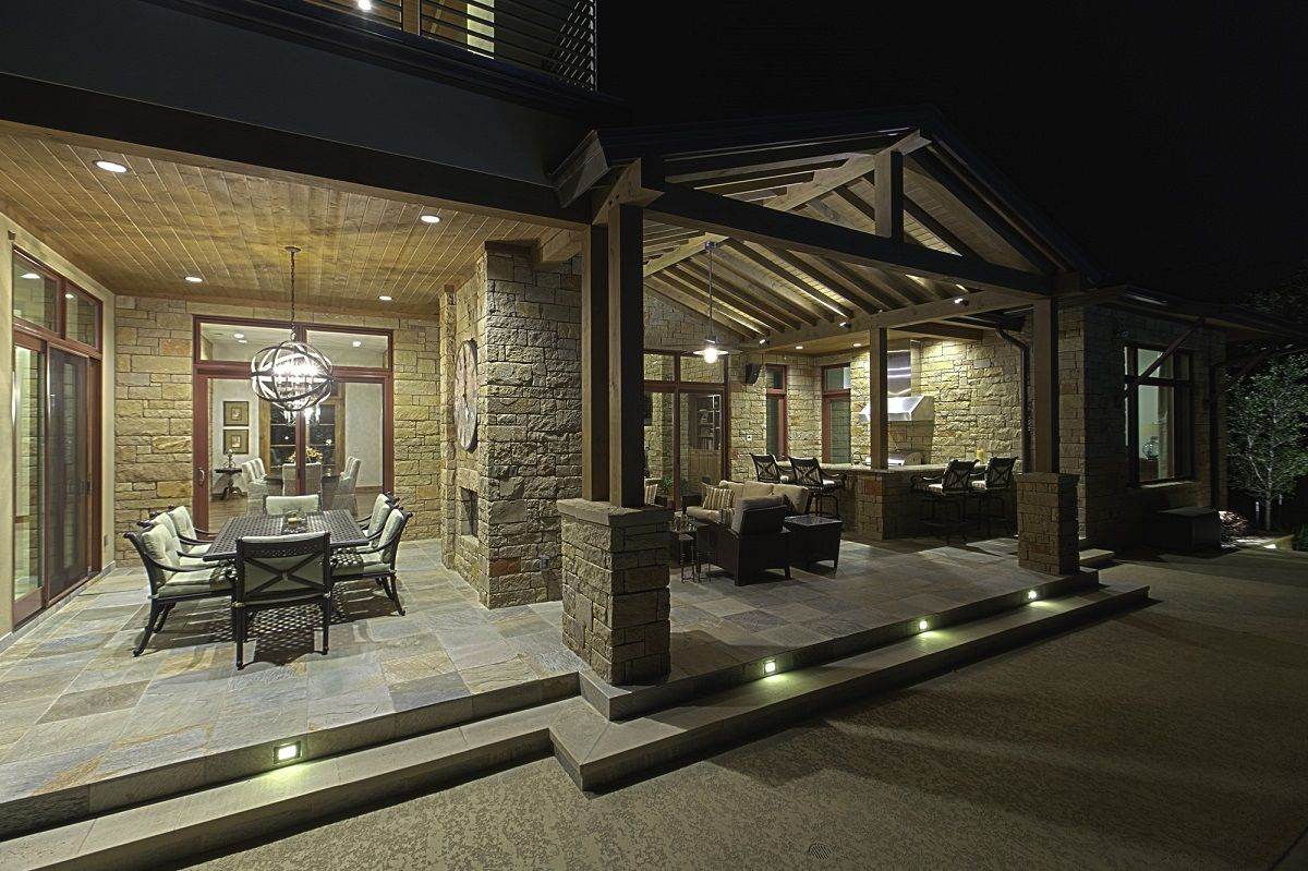 Night view of an outdoor patio with stone columns, seating, and overhead lighting.