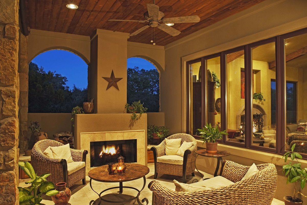 Outdoor seating area with a fireplace, wicker furniture, and evening sky.