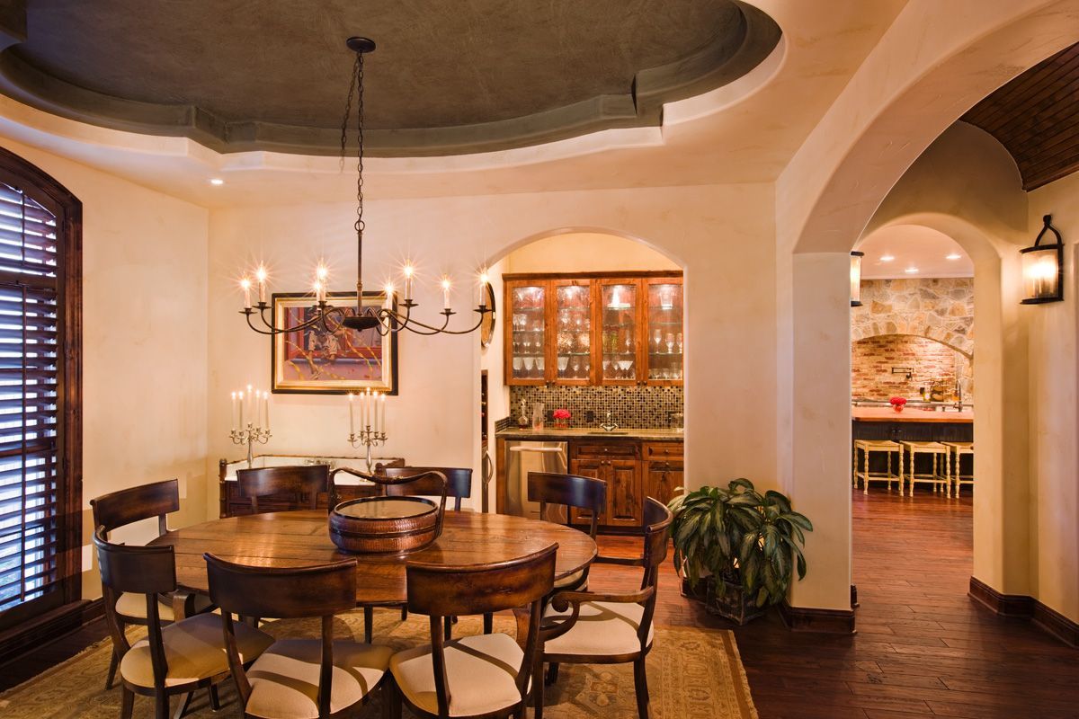 Elegant dining room with dark wood table, chandelier, and arched doorways.