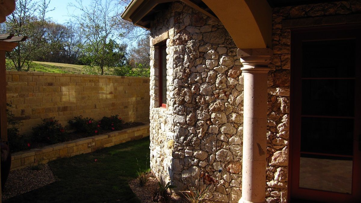 Stone building exterior with arched entry, window, and grass.