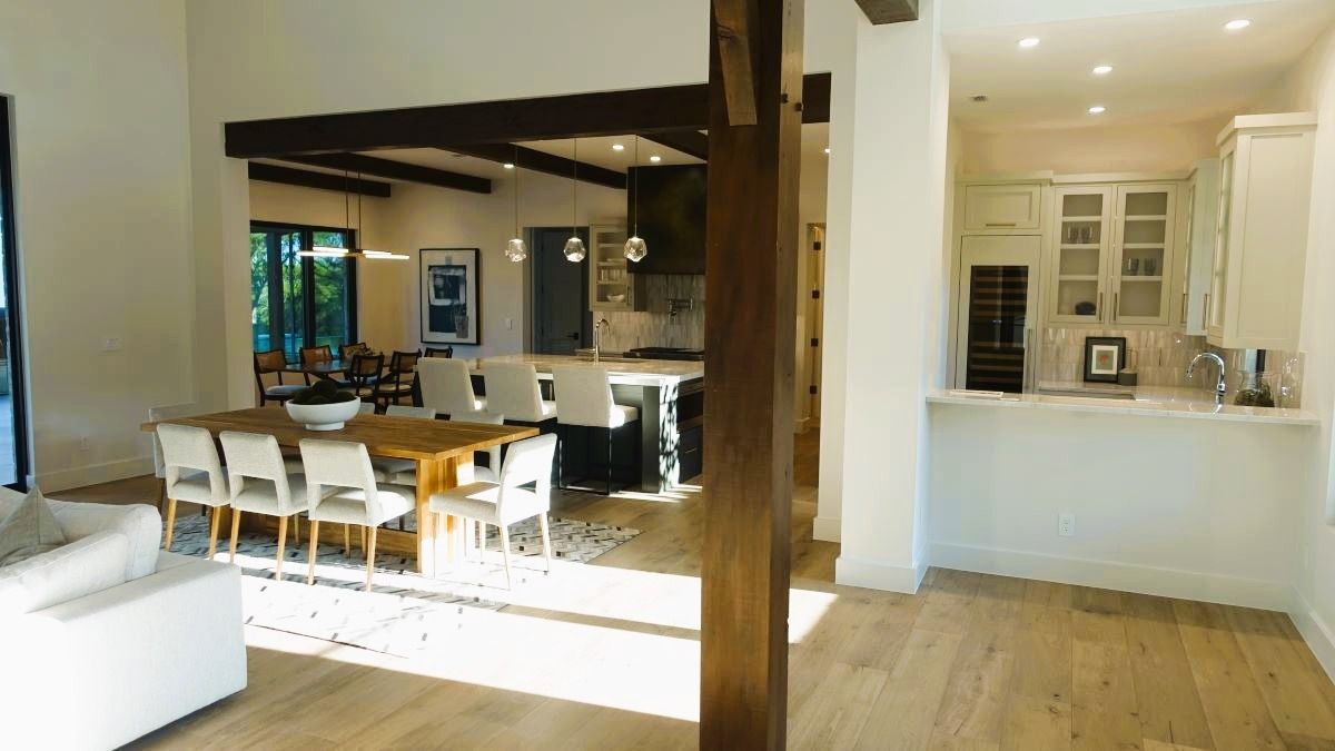 Open-concept kitchen/dining area. Features a dining table with chairs, kitchen island with stools, and hardwood floors.