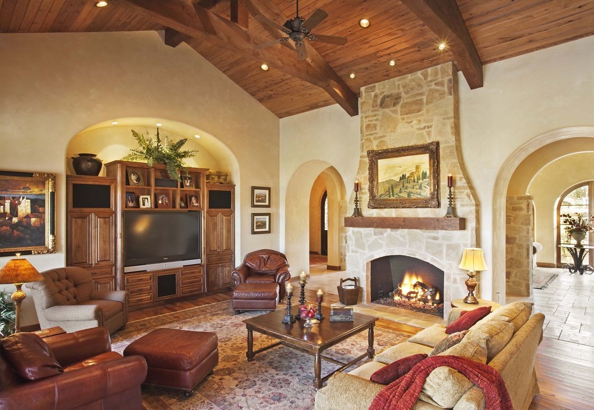 Living room with stone fireplace, wood beams, TV cabinet, and leather furniture.