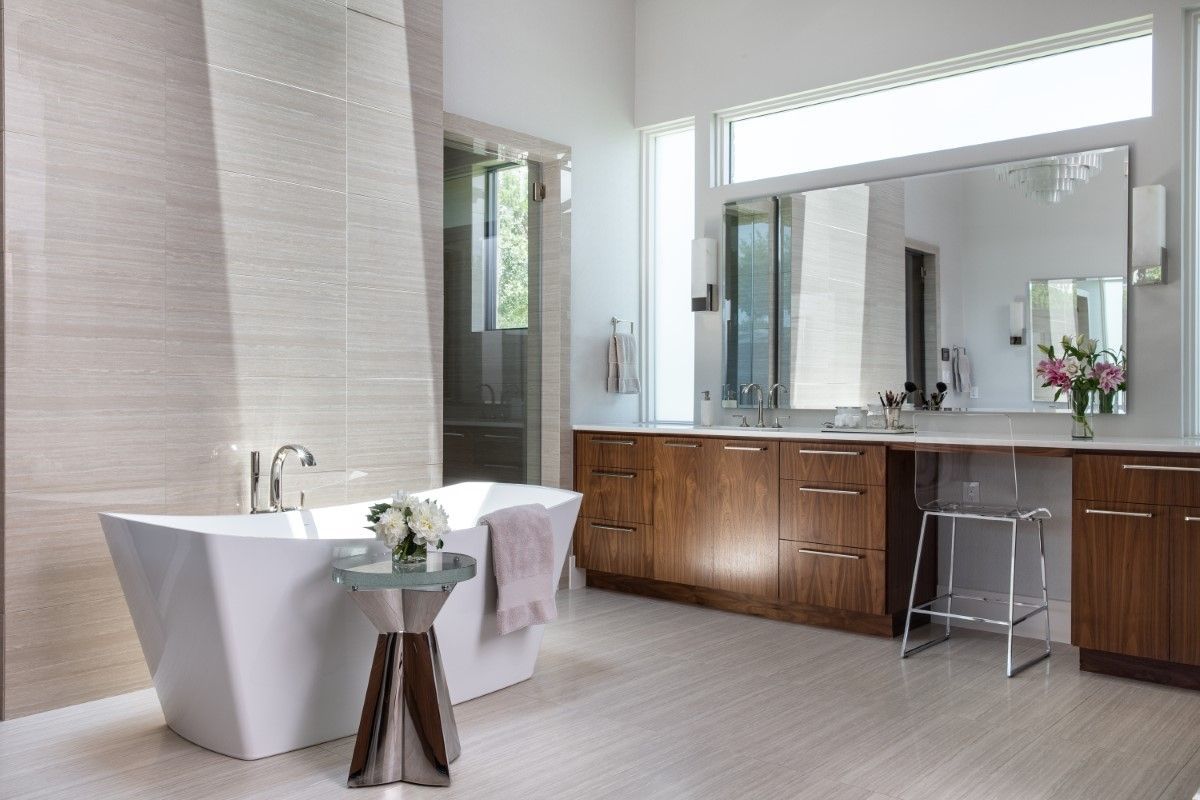 Modern bathroom with a white tub, wood vanity, and large mirror.