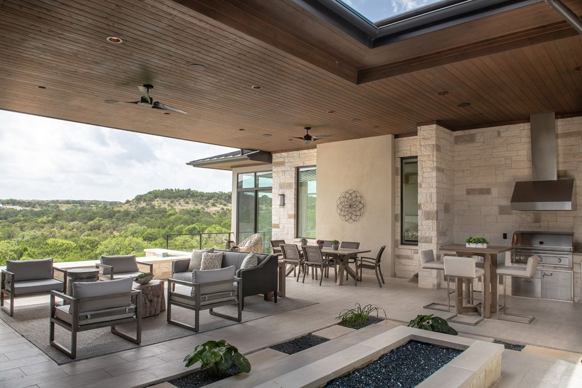 Outdoor patio with seating, dining, and a grill overlooking a landscape view.