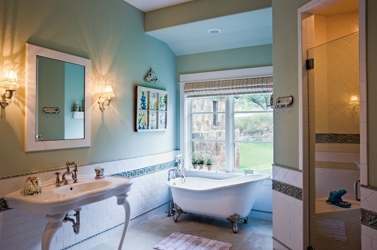 Elegant bathroom with clawfoot tub, pedestal sink, and light blue walls.