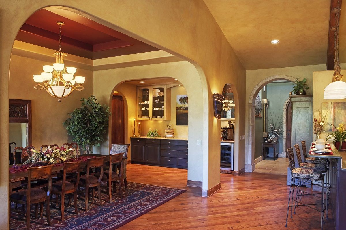 Open-concept dining room with arched doorways, hardwood floors, and a chandelier.