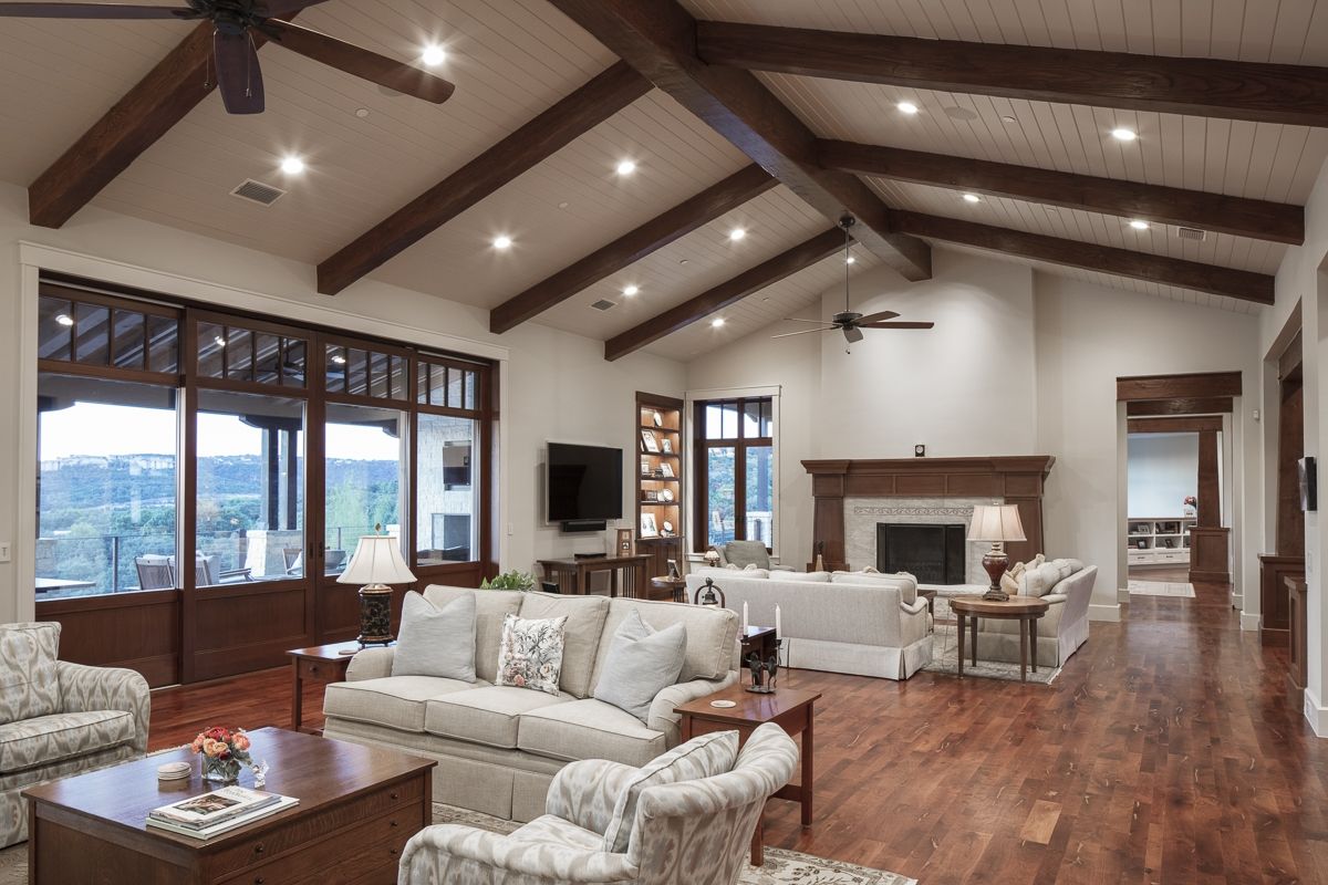 Spacious living room with wood beams, fireplace, and large windows overlooking a scenic view.