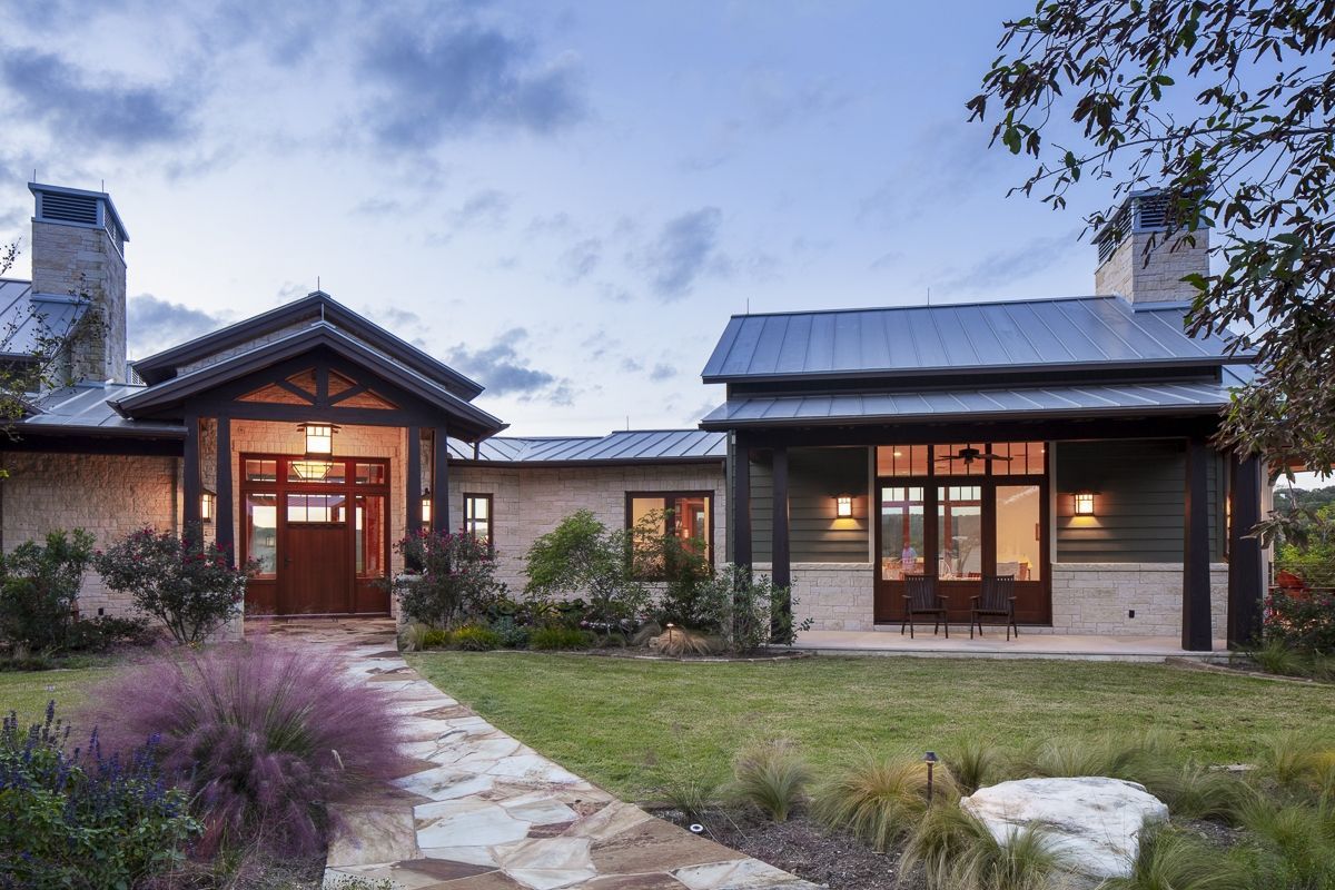 Stone and green ranch house with stone path, lawn, and dusk sky.