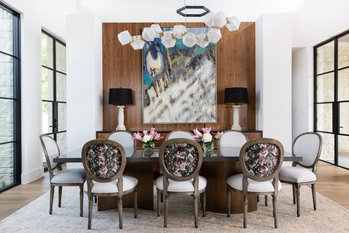 Formal dining room with wood table, chairs, artwork, lamps, and a unique chandelier.