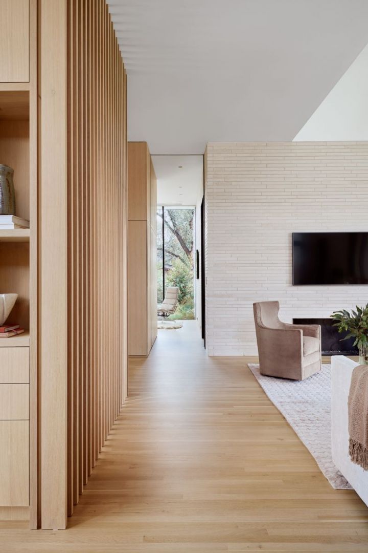Hallway with light wood floors and a neutral color scheme, leading to an outdoor view.