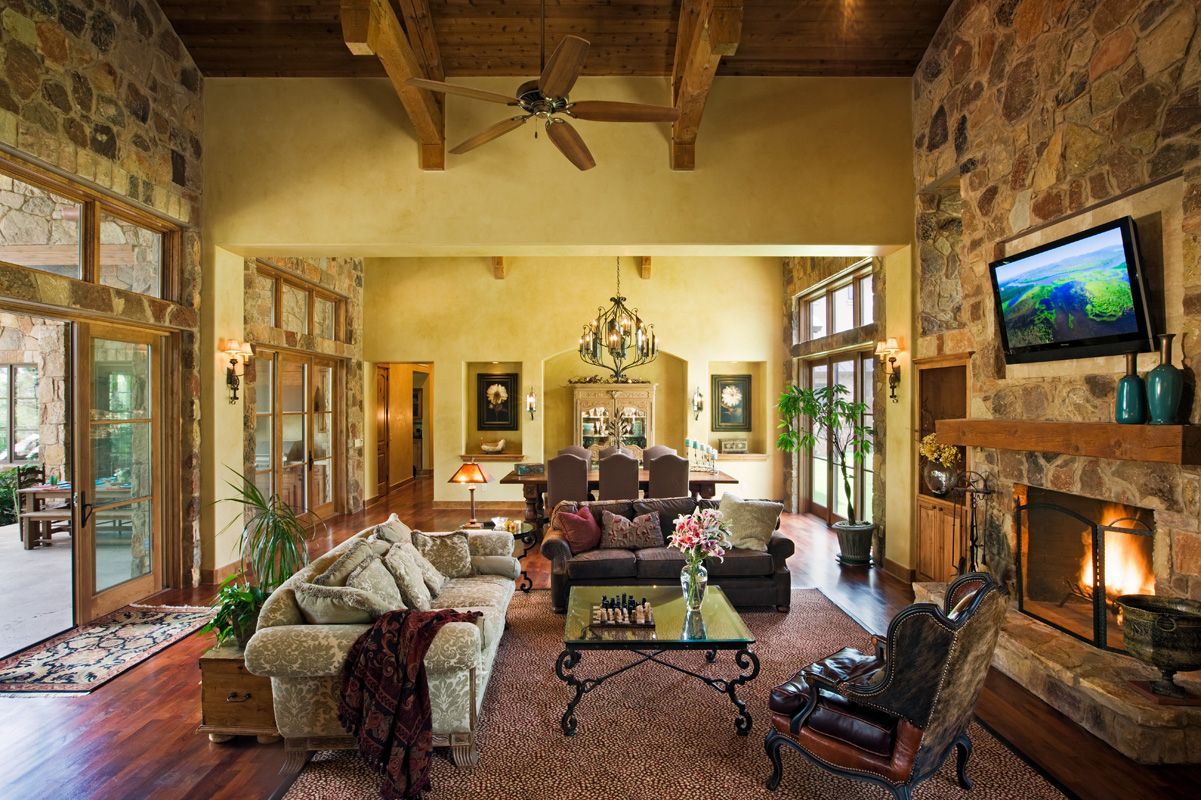 Luxurious living room with stone walls, fireplace, and open view to the dining area.