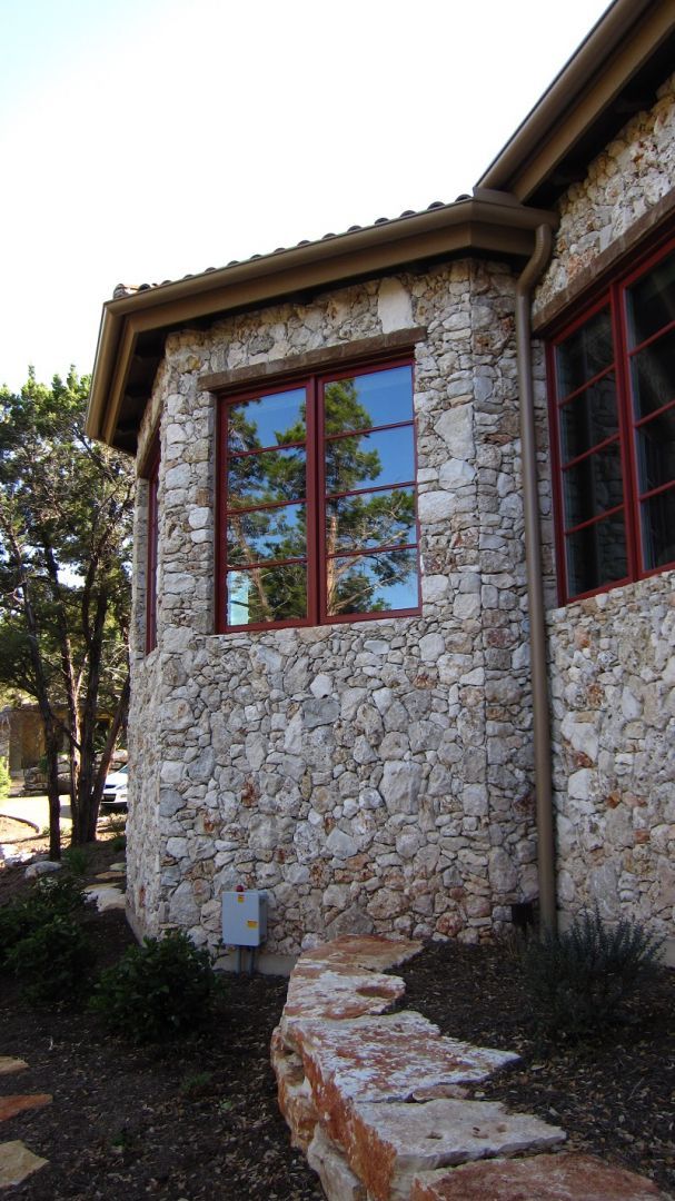 Stone house exterior with red-framed windows, set on a pathway of stone steps.