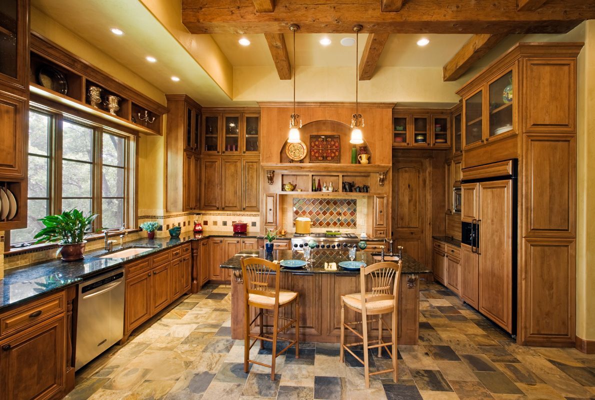 Rustic kitchen with wood cabinets, island, and tile floor.