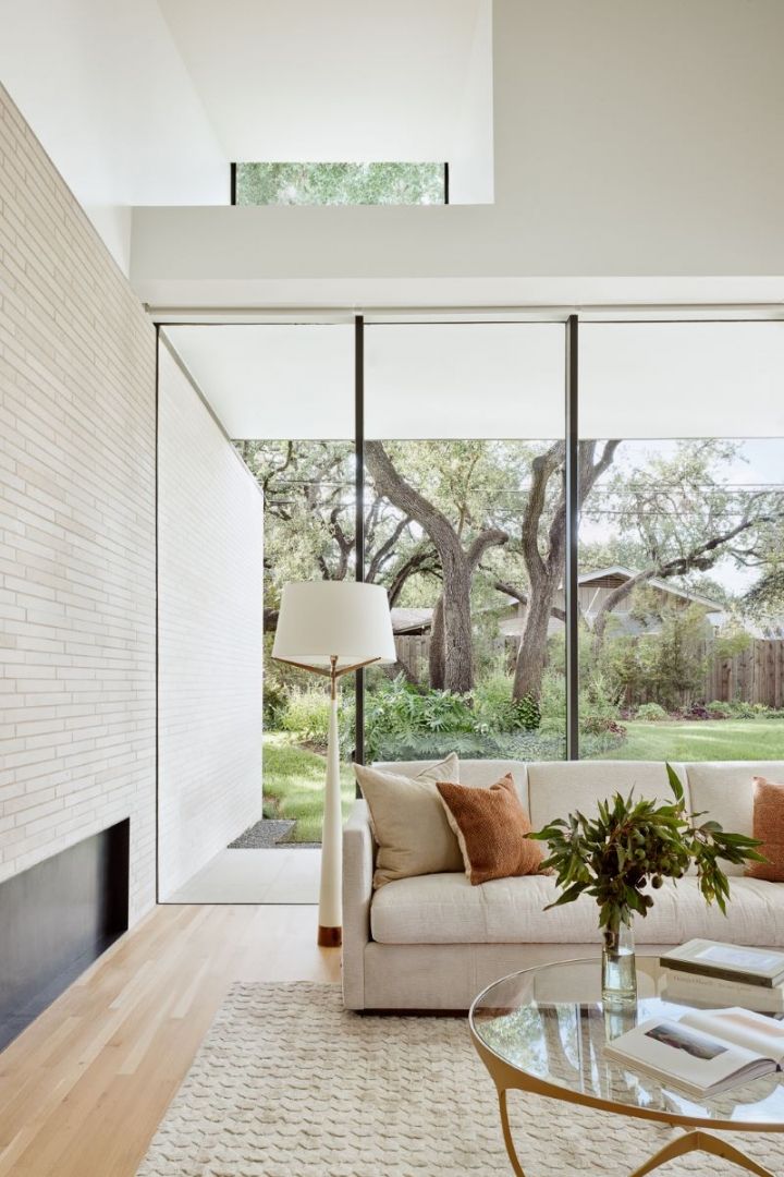 Modern living room with large windows, white sofa, and a brick wall.