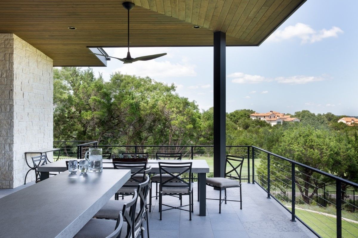 Outdoor patio with a table and chairs overlooking a green landscape.