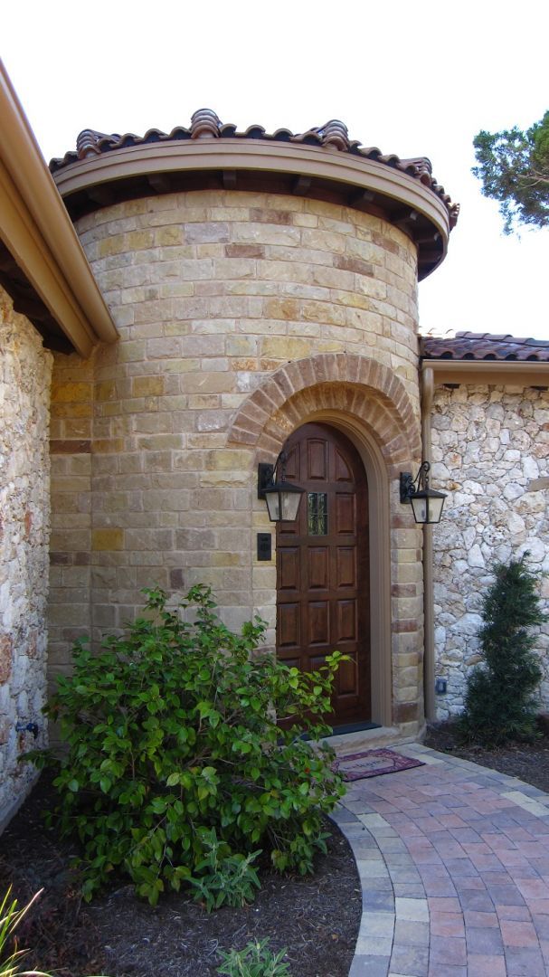 Stone entry with arched wooden door and circular tower.