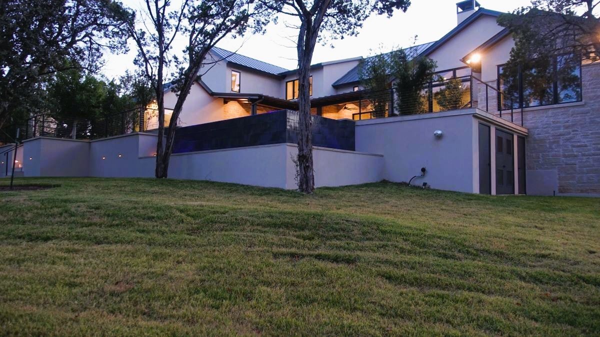 A multi-story house with a manicured lawn in front. Dusk lighting.