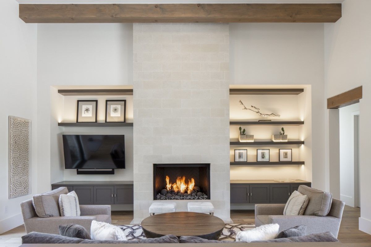 Modern living room with fireplace, built-in shelves, seating, and a wooden beam.