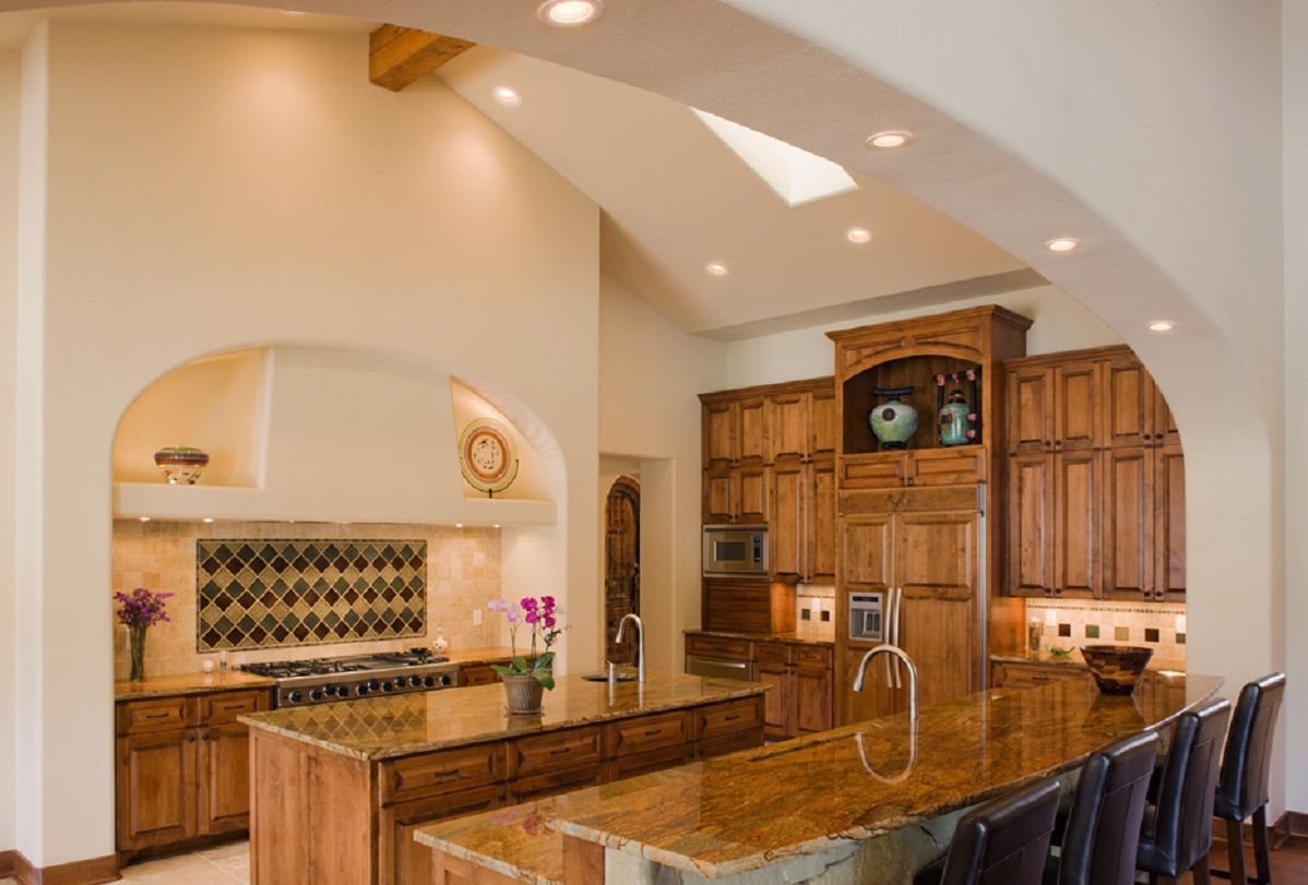 Spacious kitchen with wood cabinets, two granite islands, and recessed lighting.
