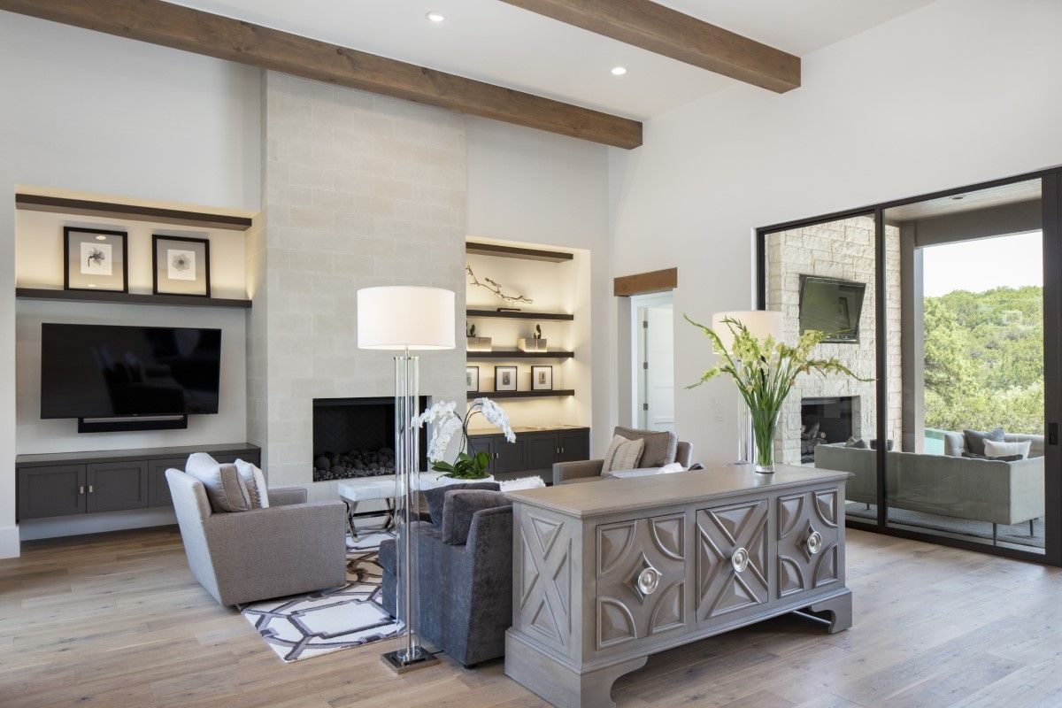 Spacious living room with fireplace, TV, desk, and open doors to a view of greenery.