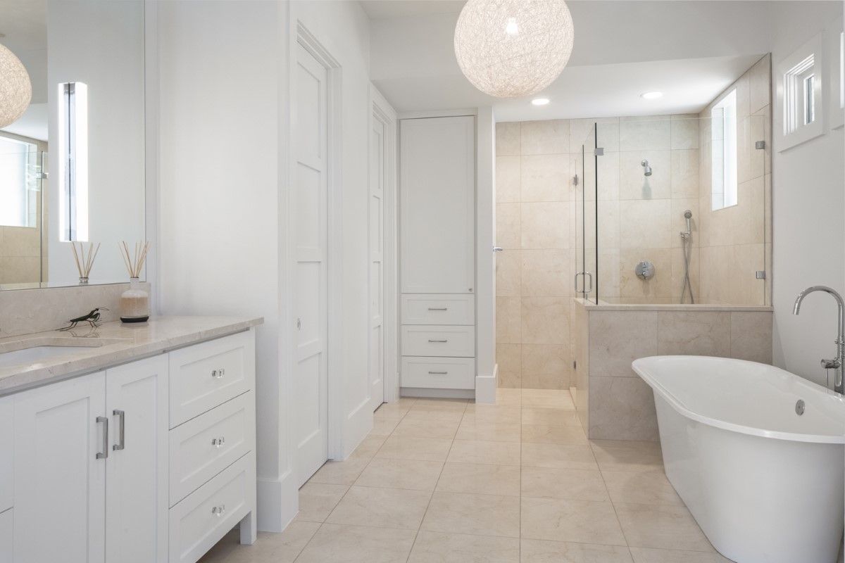 White bathroom with a freestanding tub, glass shower, and vanity.