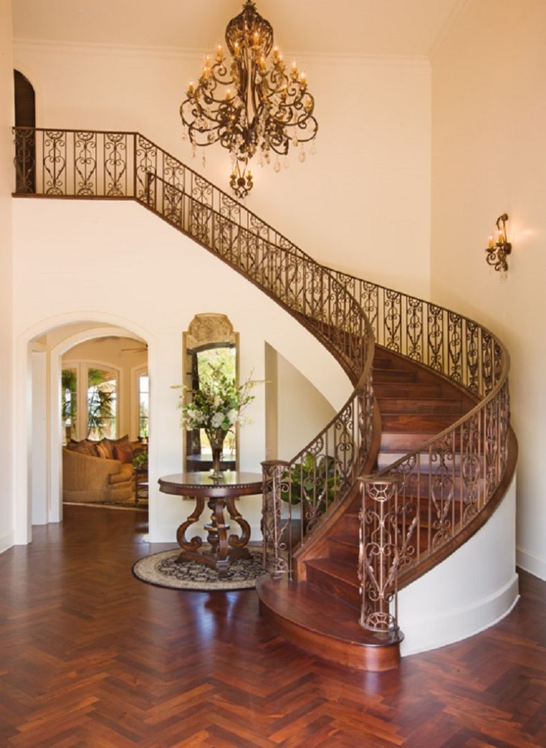 Grand foyer with a curved staircase, chandelier, and decorative table.