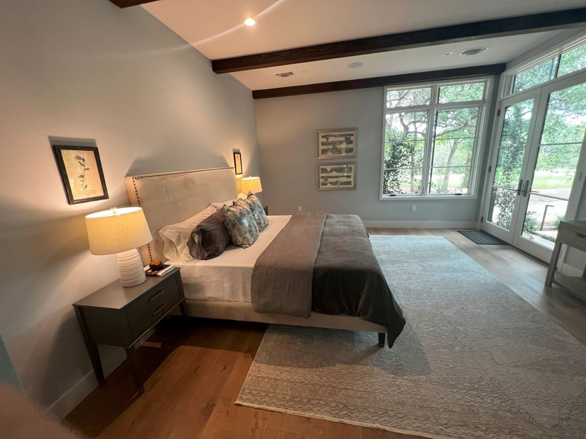 Bedroom with bed, nightstands, large window with view, and wooden floors.