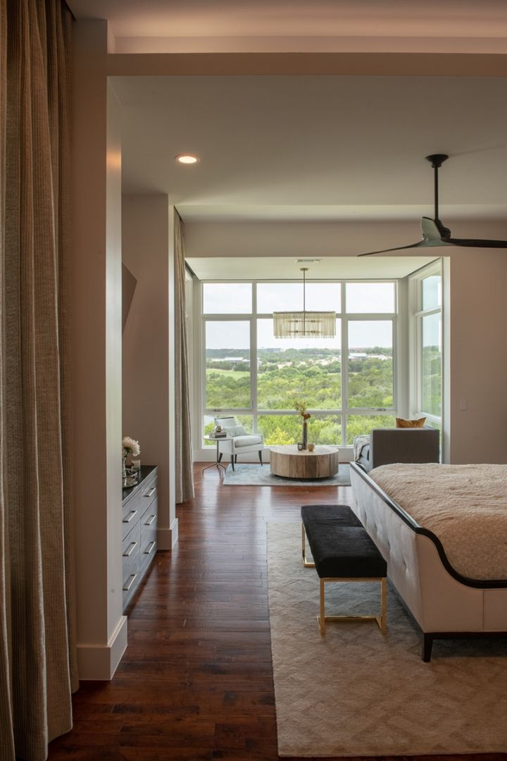 Bedroom interior with a large window overlooking a green landscape. Includes a bed, bench, and furniture.