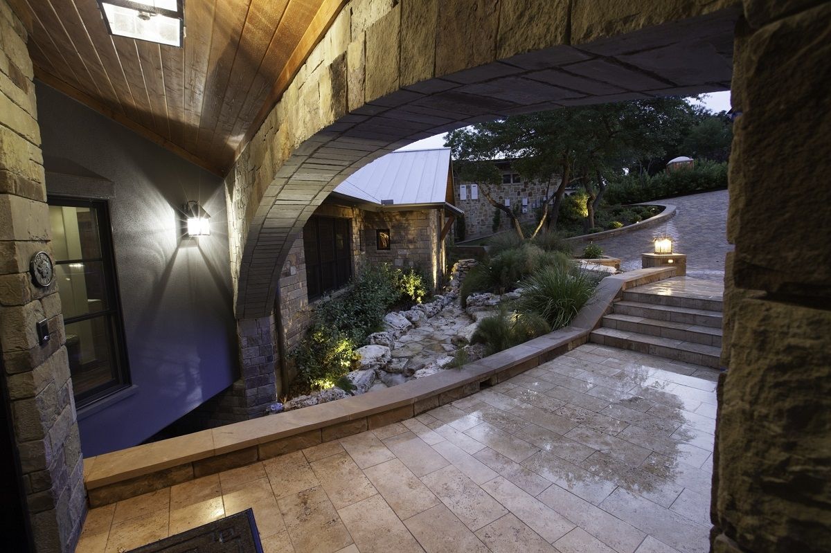 Stone archway leading to a patio with stairs and landscaped garden.