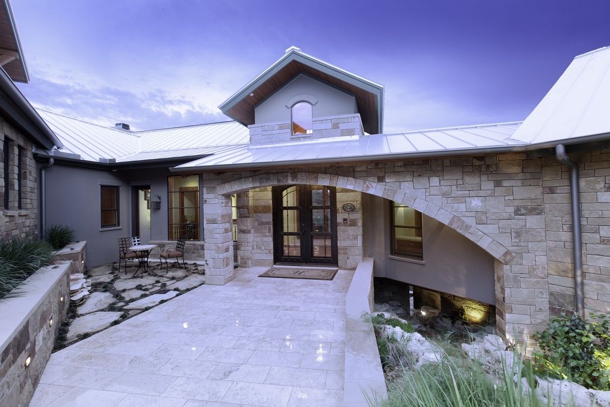 Stone and stucco home exterior with arched entrance and pathway.