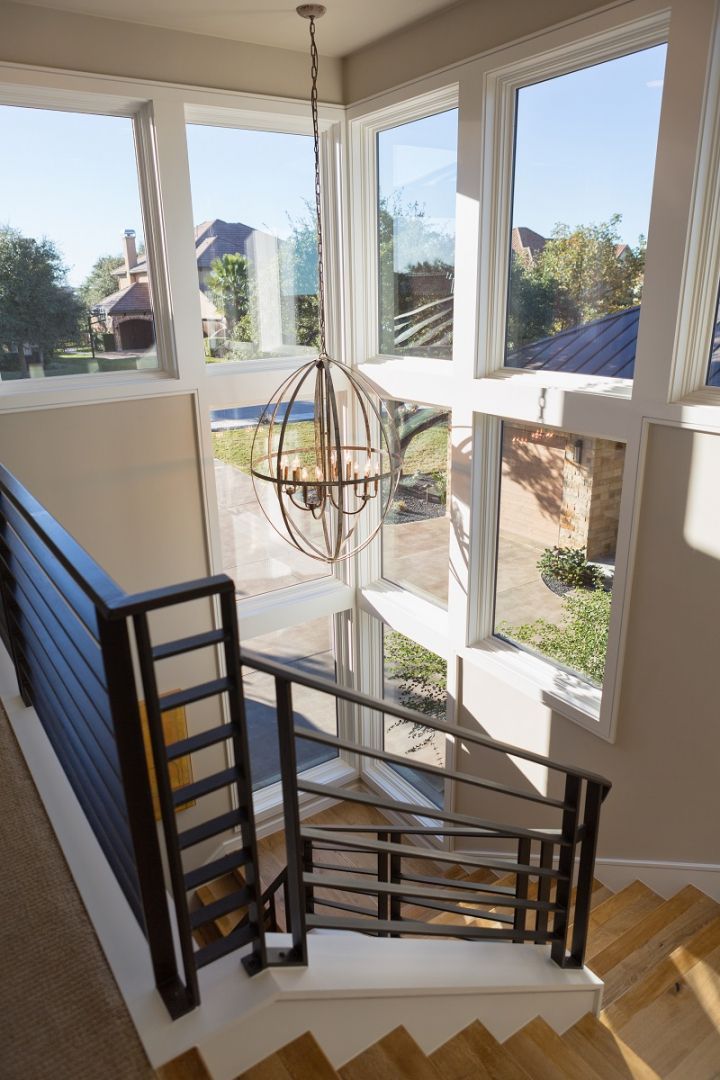 Stairwell with large windows, modern metal railing, and a spherical light fixture; natural light floods the space.