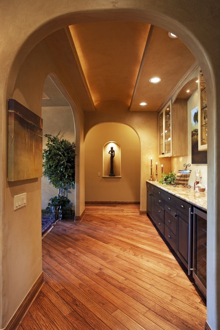 Hallway with arched openings, hardwood floors, and built-in cabinets along one wall.