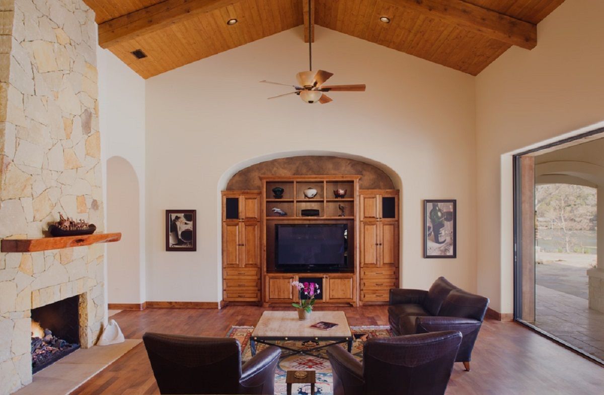 Living room with a fireplace, entertainment center, and seating area, with wood ceiling.
