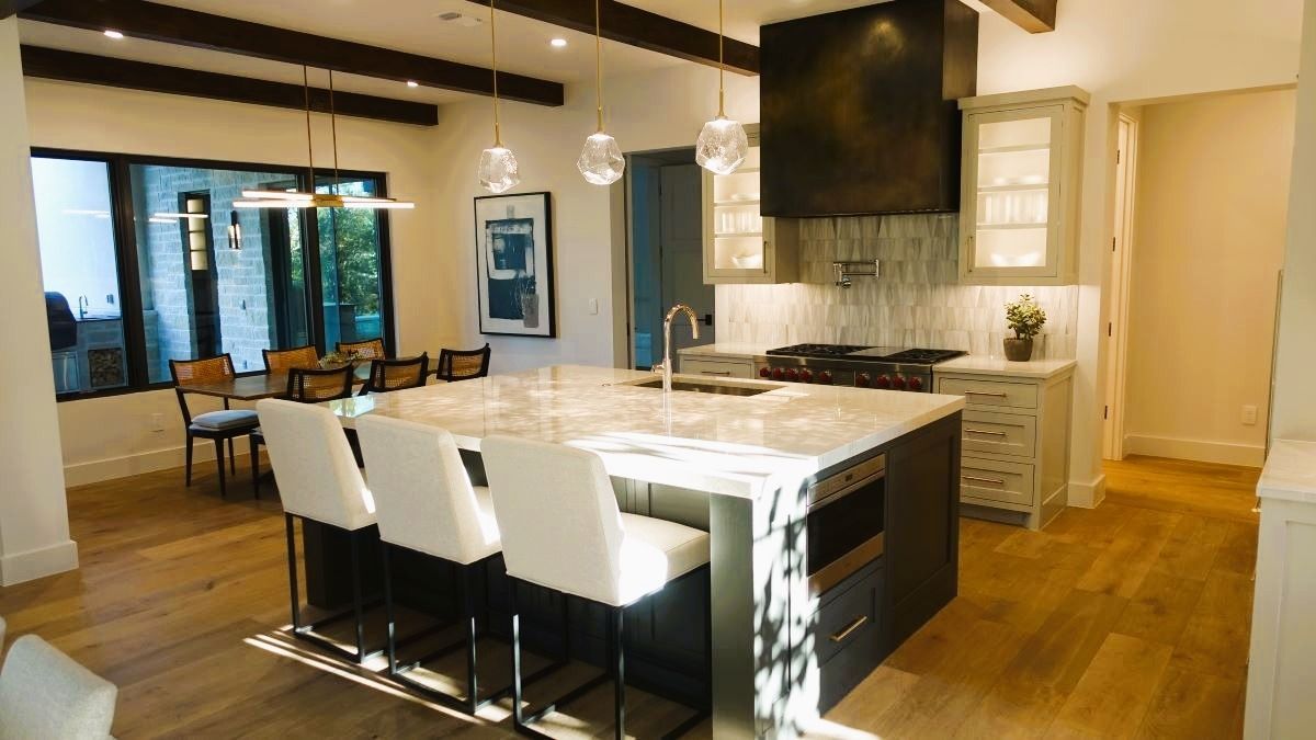 Modern kitchen with island, seating, stove, and dining area.