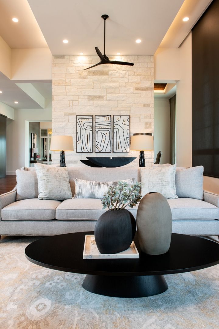 Living room with light gray sofa, black coffee table, stone wall, and decor.