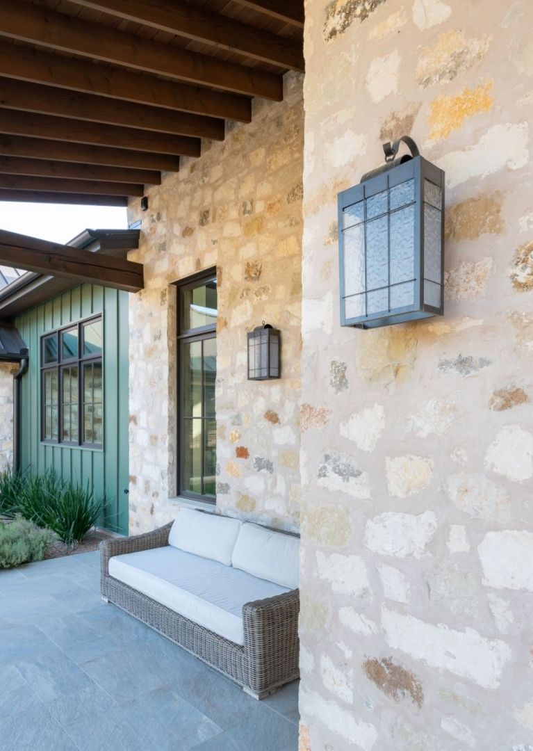 Stone exterior with a seating area and lantern-style wall lights.