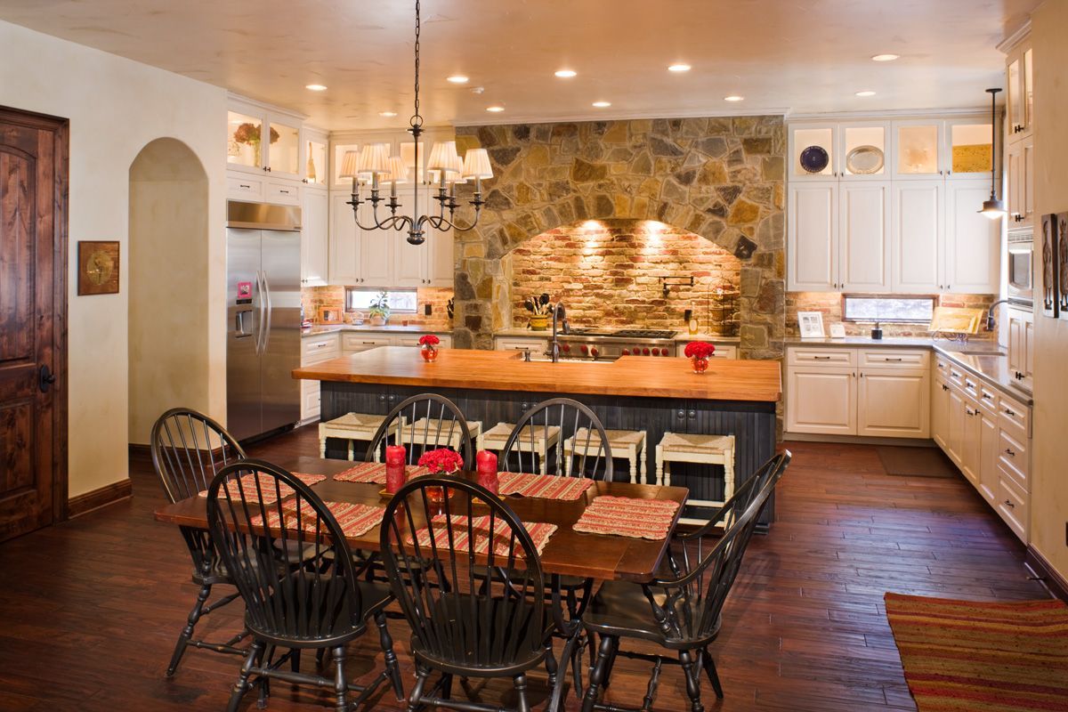 Kitchen with stone wall, wooden counters, table, chairs, and a chandelier.