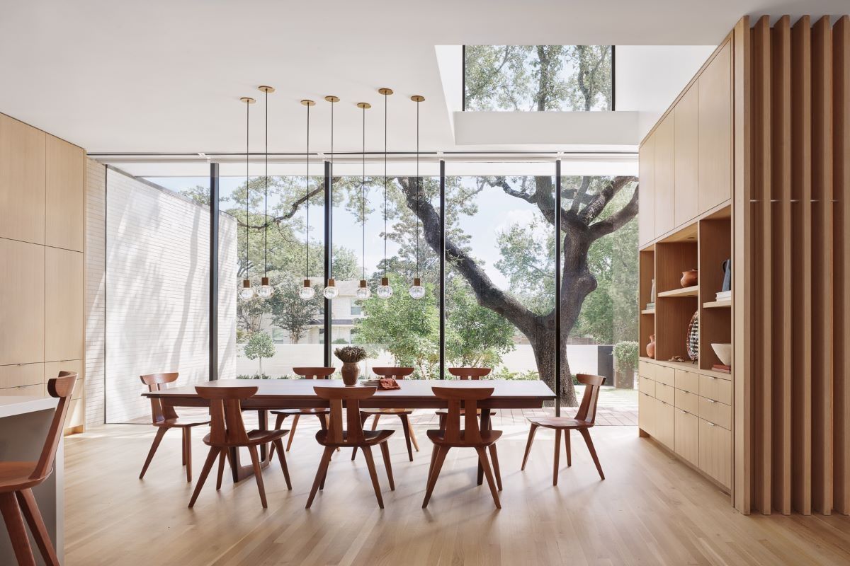 Dining room with large windows, a wood table and chairs, and pendant lights.